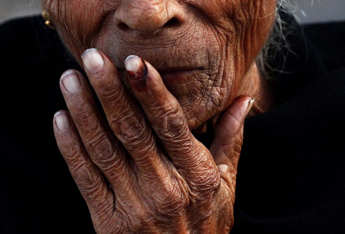 FILE PHOTO: An elderly woman places her ink-marked finger on her lips after casting her vote outside a polling booth during the state assembly election in Delhi